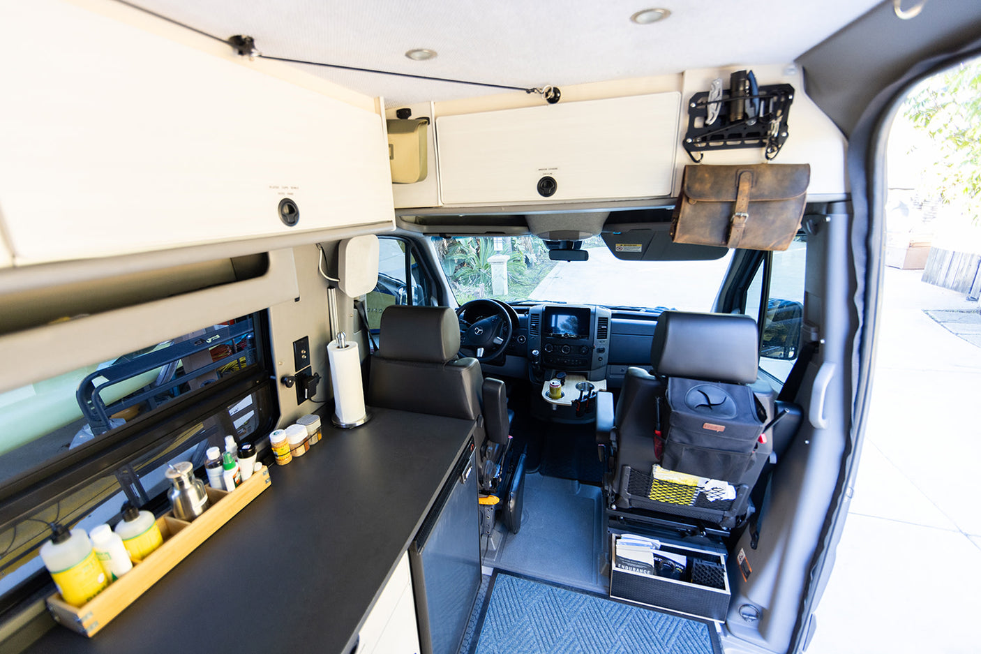 Detailed RV rental interior: custom camper van conversion with cockpit, compact kitchen, and smart storage solutions for travel.