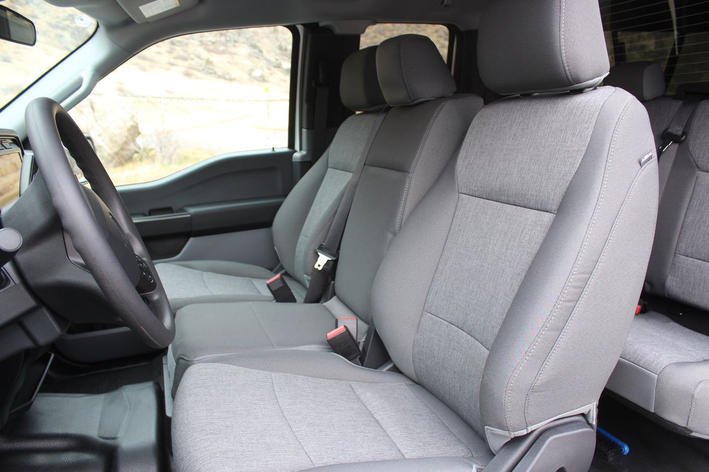 Inside a spacious grey-seated vehicle for your rv rental, showing steering wheel & outdoor scenery.