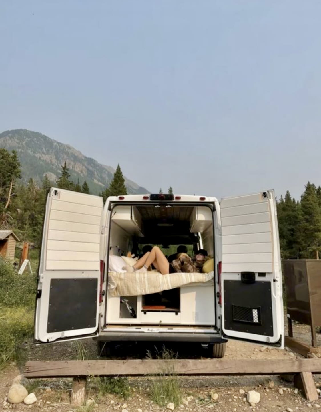 stratified cliffs dominate the background under a clear sky.|RV rental interior features a functional dining/workspace with a laptop