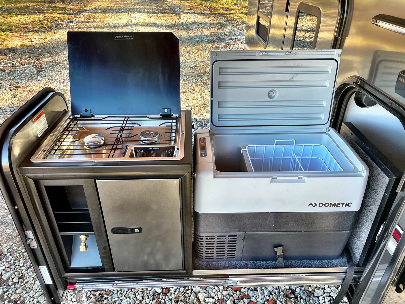 An RV rental's dream: Dometic outdoor kitchen with a two-burner stove and a large portable fridge, perfect for camping!