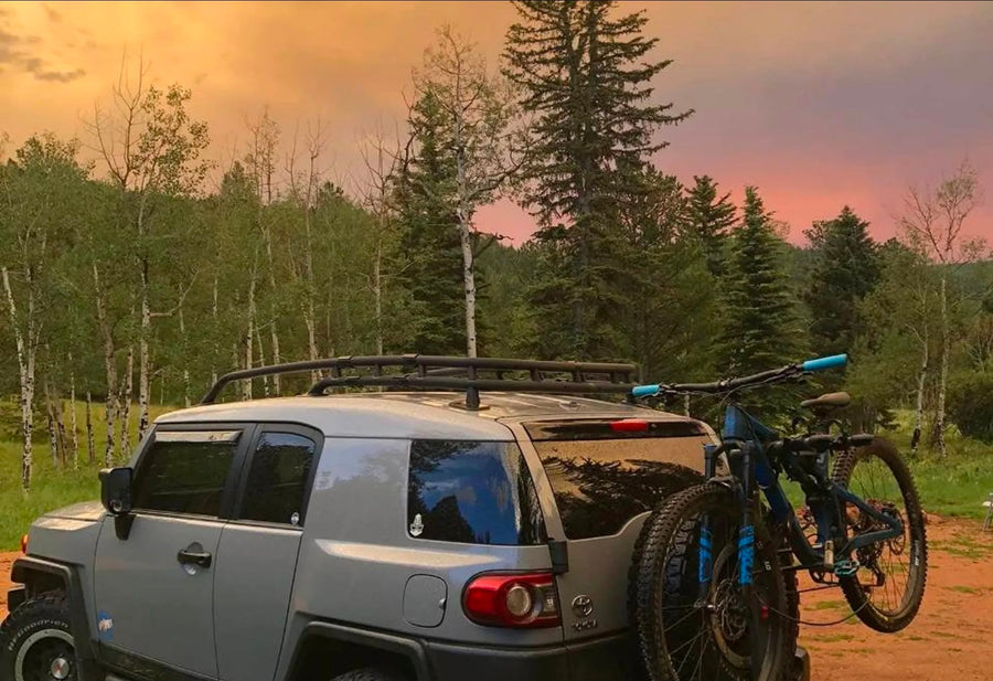 A grey FJ Cruiser with mountain bikes on a dirt path