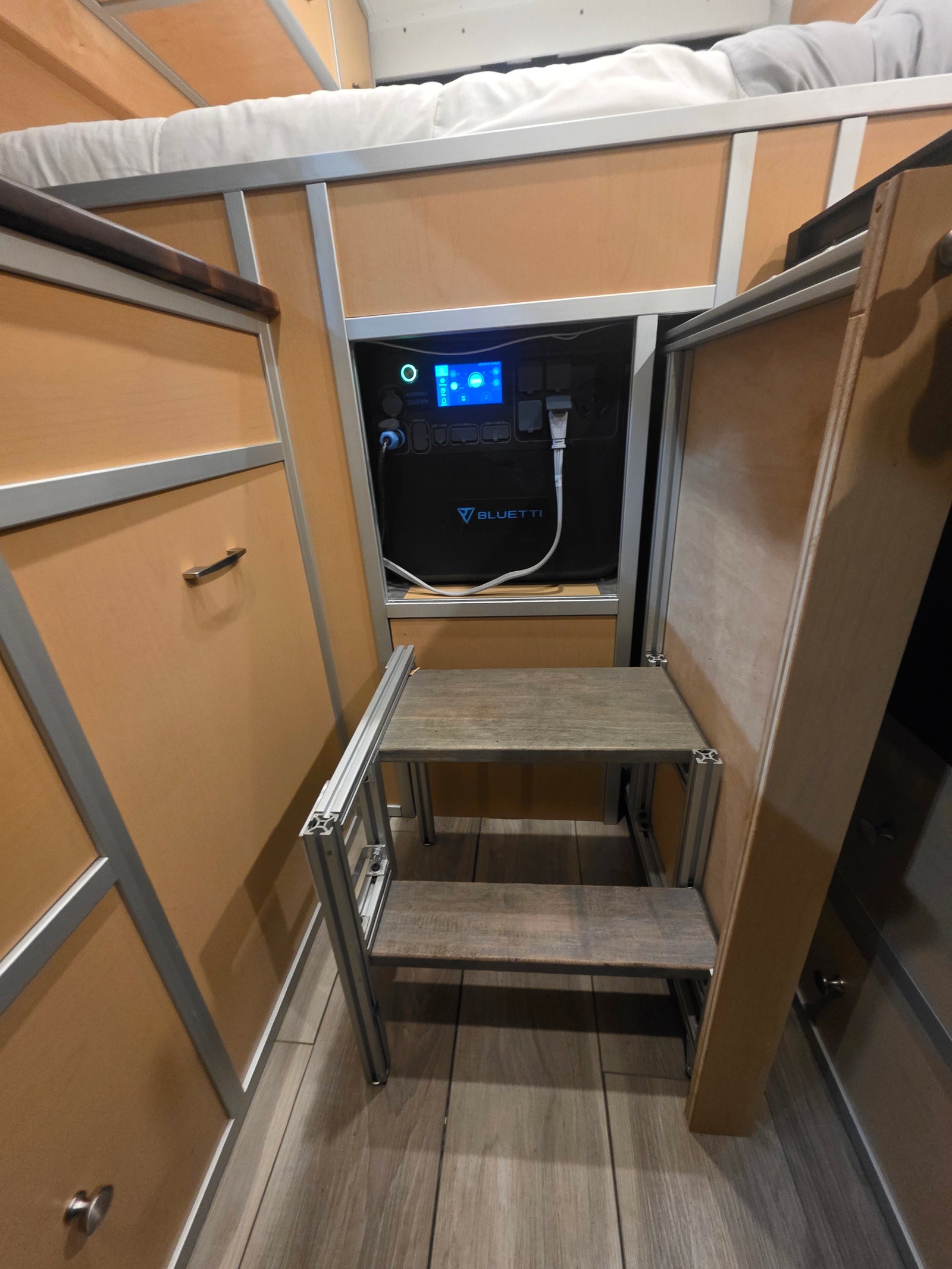 Bluetti power station, plugged in and integrated into a compact RV rental interior, with a custom two-step ladder & bunk bed.