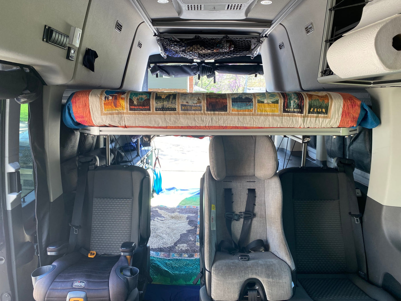 RV rental interior with a cozy bunk bed featuring National Park designs and two child car seats.