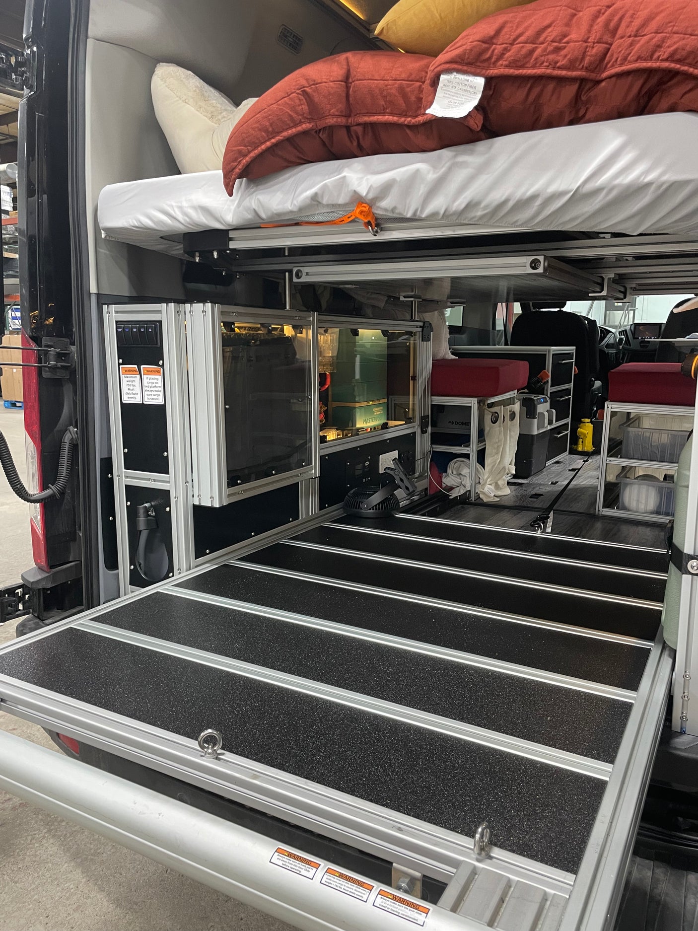 Spacious rv rental interior with modular storage, bed platform, and pull-out cargo tray for organized travel.