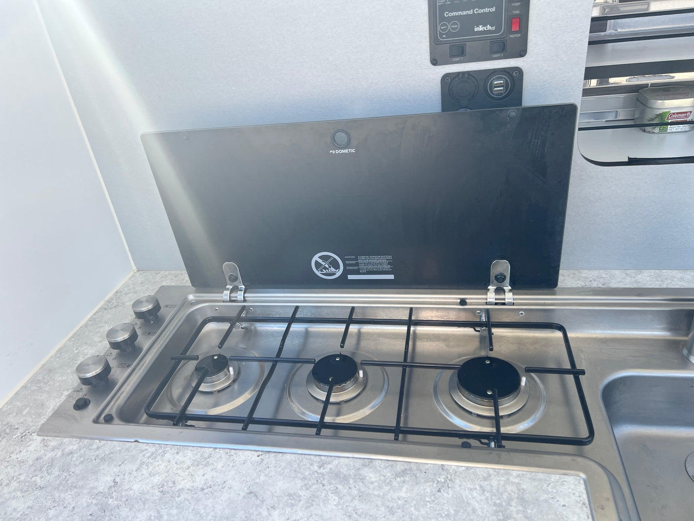 RV rental kitchen: Dometic stove/sink unit, control panel, and USB ports for comfortable cooking on the go.