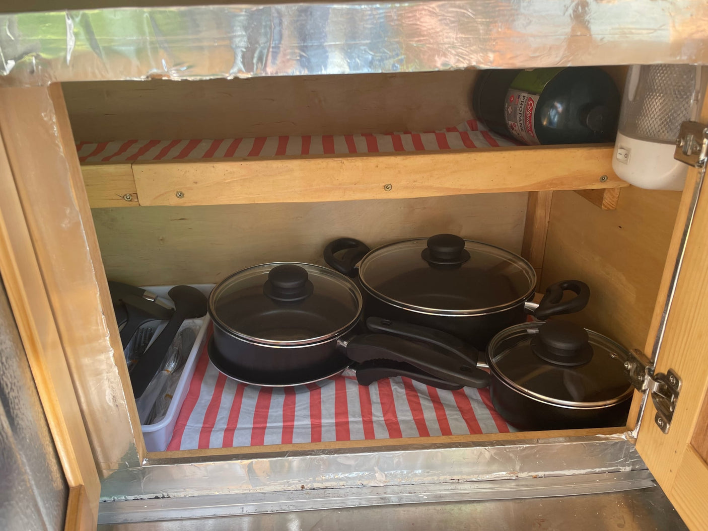 and lower wood cabinets.|Open rear hatch of a yellow teardrop rv rental