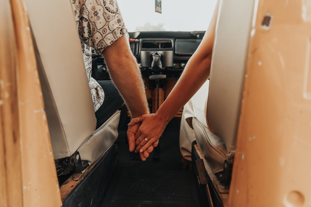 Adventure-bound rv rental: Couple's hands intertwined in their cozy vintage camper, ready for travel.