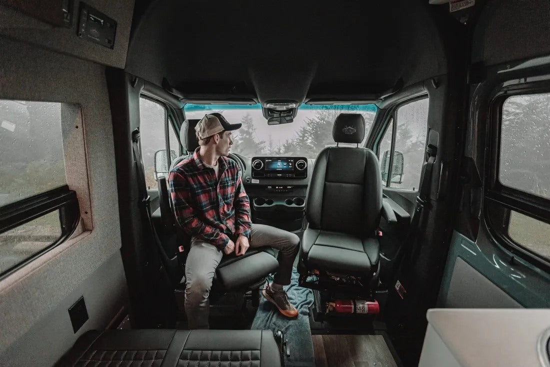 Man in an RV rental camper van, looking out at the rainy view. Ideal for cozy travels.
