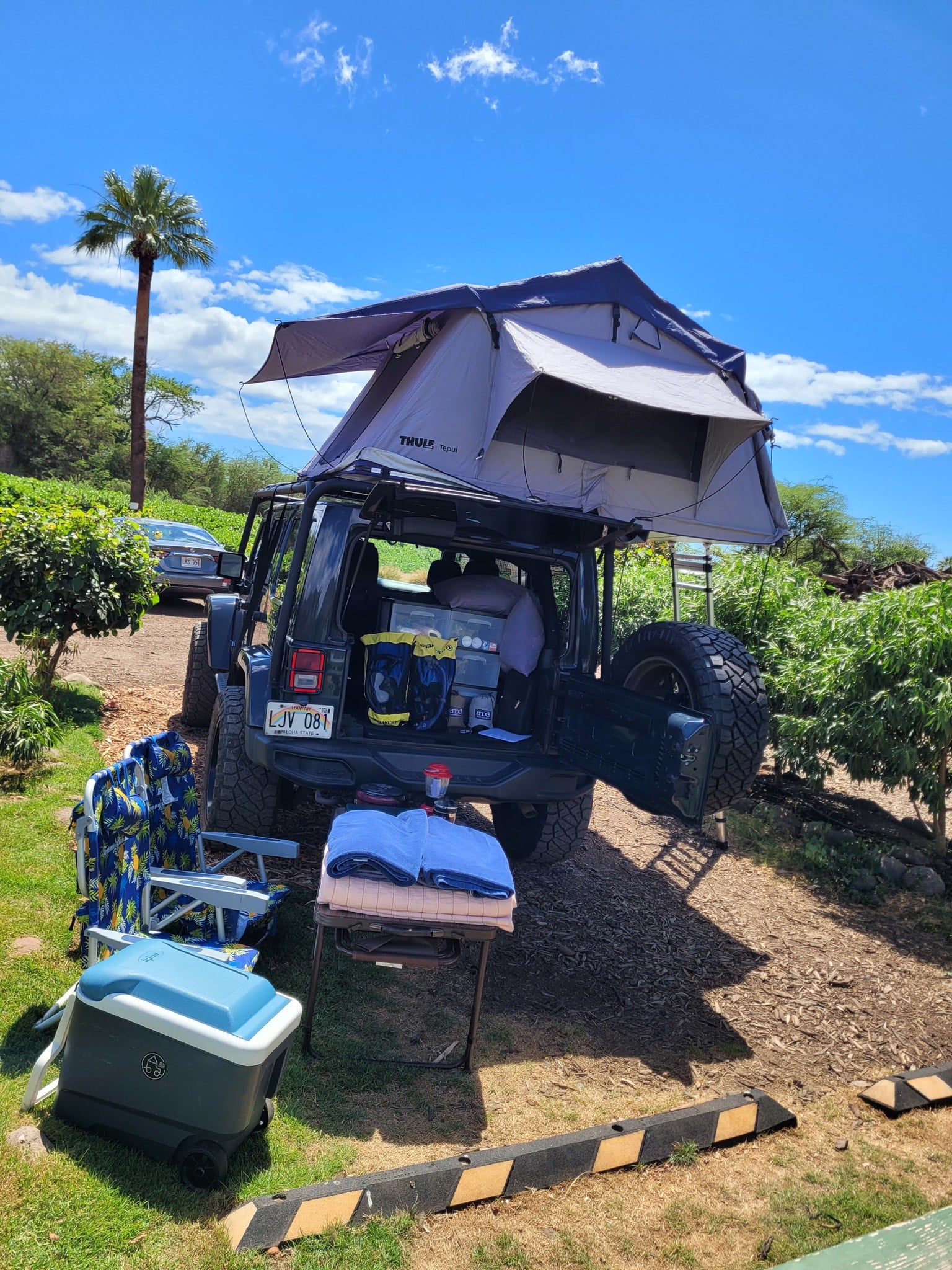 A fully equipped Jeep with a rooftop tent, chairs, and cooler, suggesting a convenient RV rental for a nature escape.