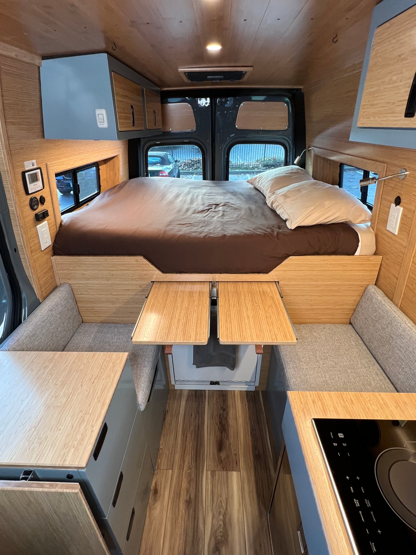 Spacious rv rental interior: bed, cozy seating with pull-out tables, integrated kitchen, and overhead storage.