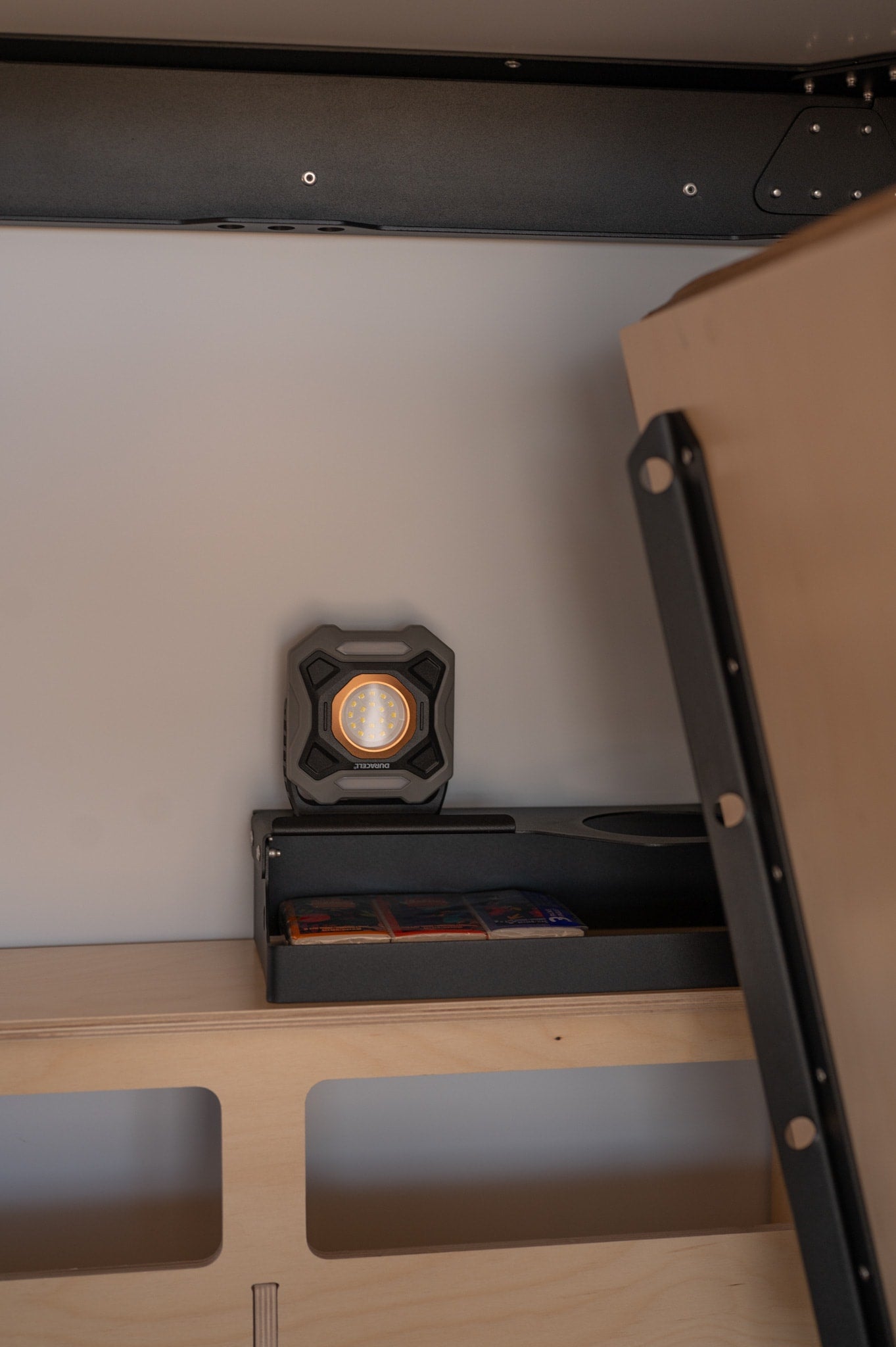 Inside an **RV rental**: a Duracell LED work light illuminating integrated storage and a cleverly designed convertible bed system.