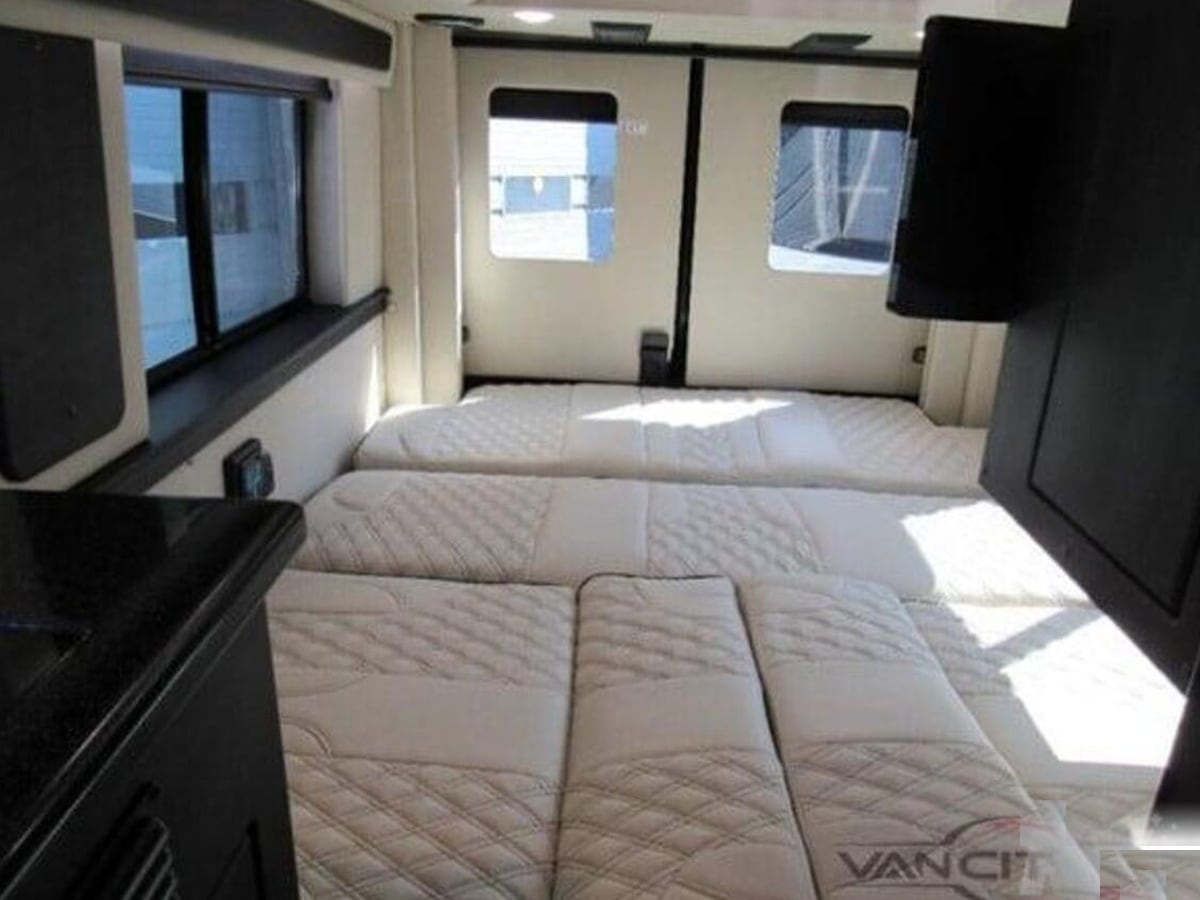 easily converting for living or sleeping.|Modern luxury RV rental interior with a large TV — photo 14