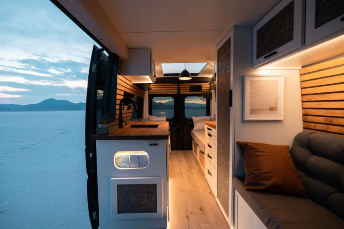 Experience mobile living! This modern RV rental interior features a kitchen, seating, and stunning salt flat views.