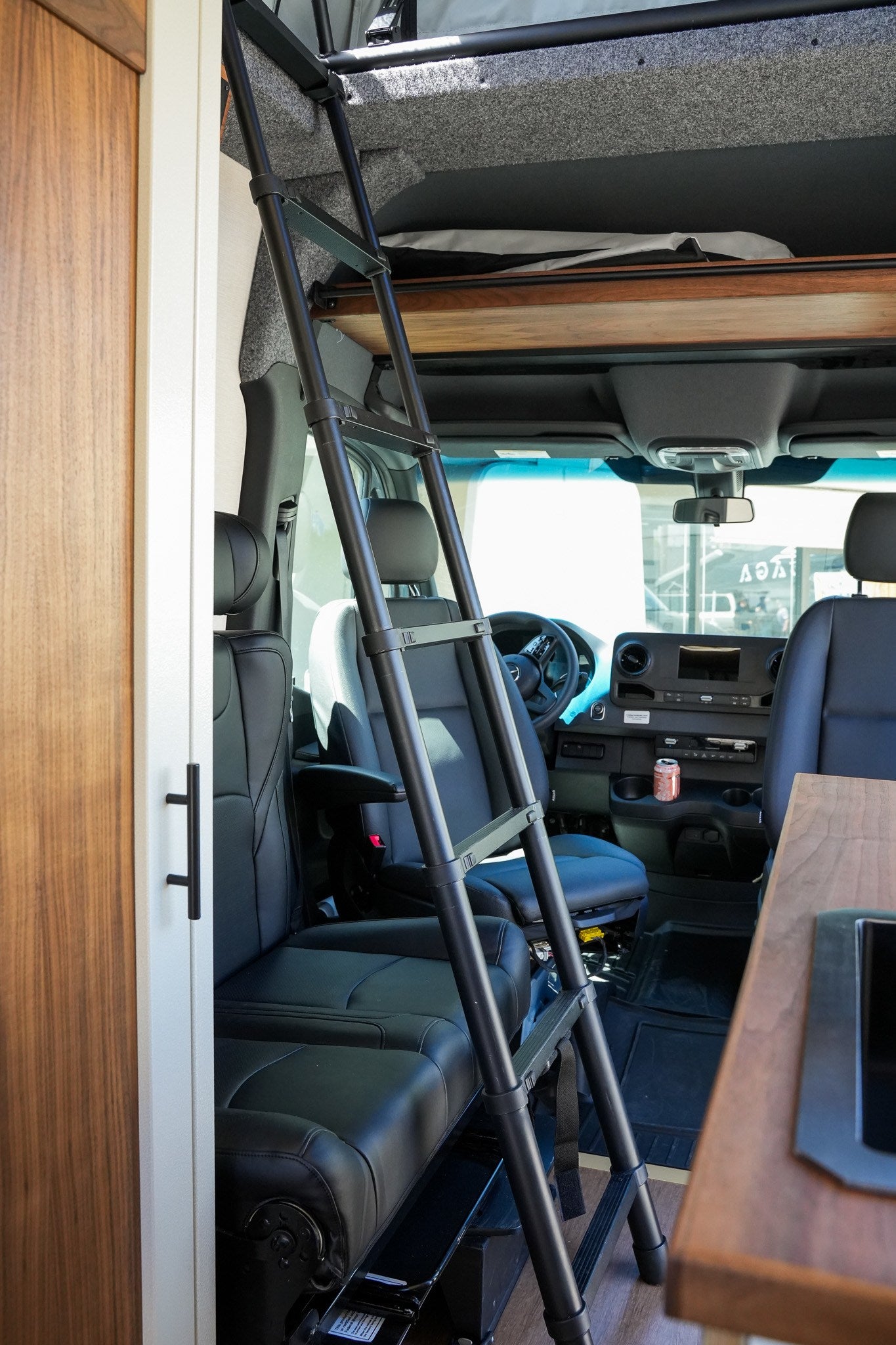 RV rental interior: ladder to upper bunk, front cockpit, and wooden kitchen area.