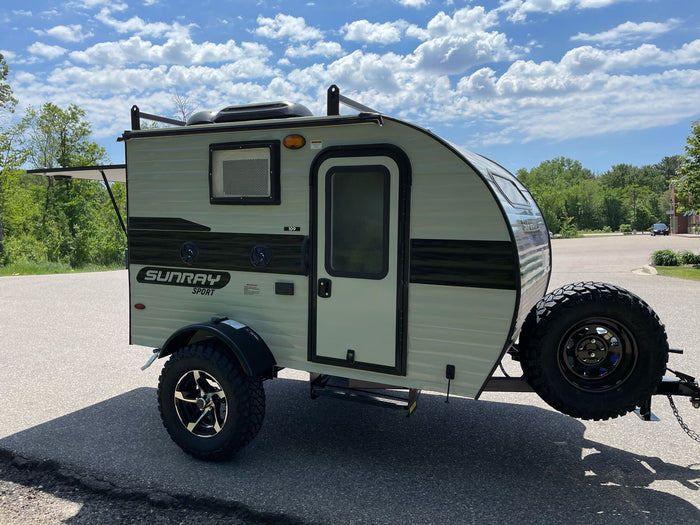 with its outdoor kitchen revealed by the open rear hatch.|Explore with this rugged light green Sunray Sport teardrop camper