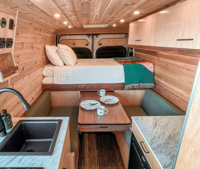 beige Vanish RV rental is parked in a lush forest