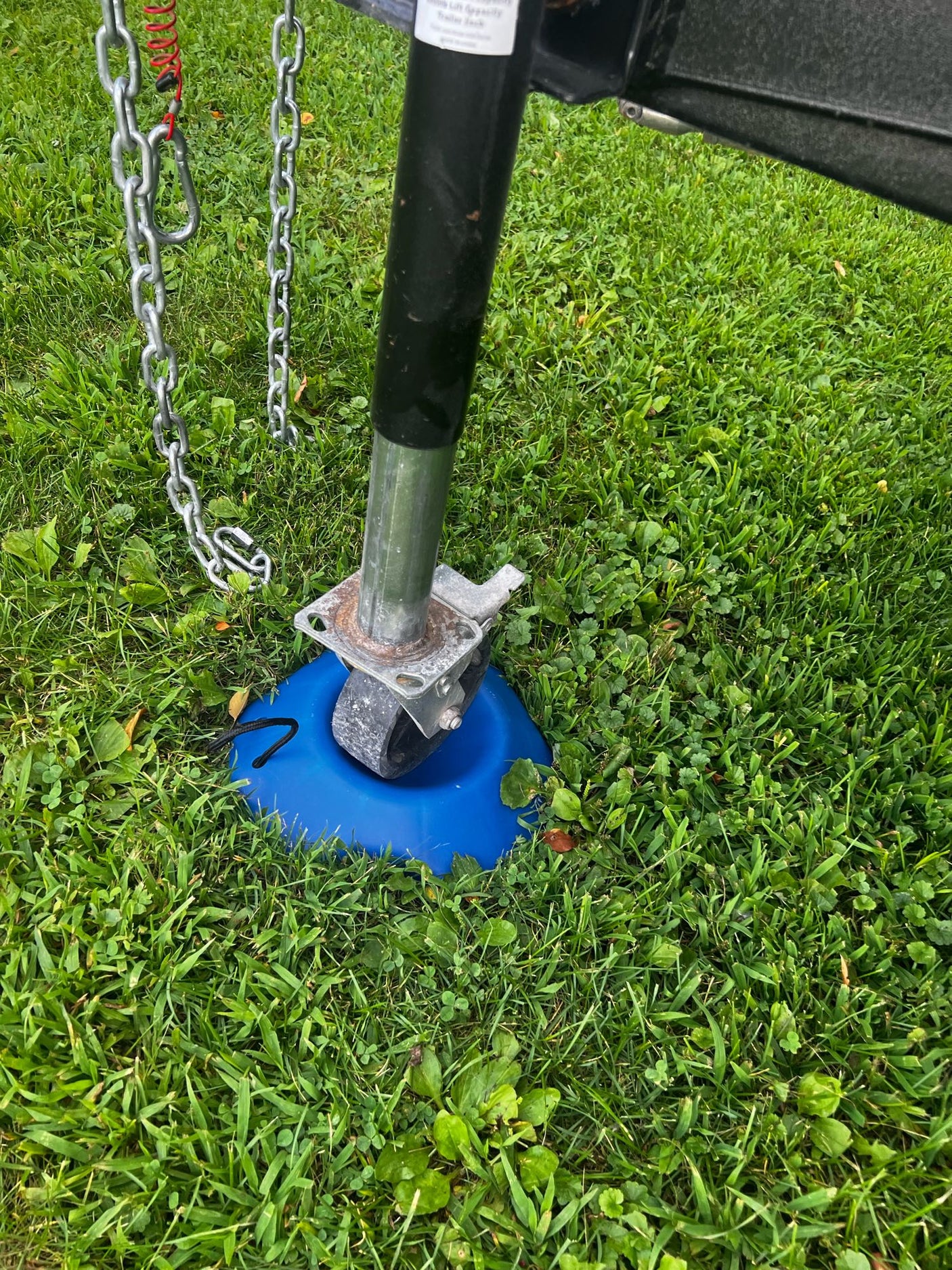 RV rental trailer jack on a blue base in the grass with safety chains, ensuring stable parking.