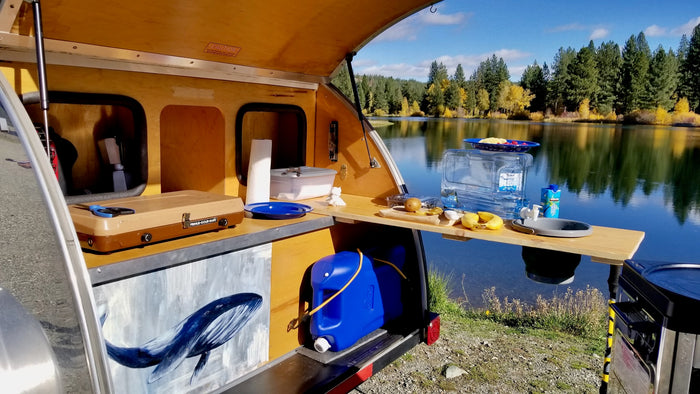 set by a scenic lake and mountains.|Enjoy nature with this RV rental! A shiny teardrop trailer by a lake