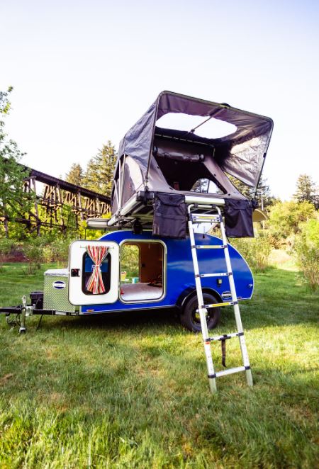 Experience compact outdoor adventures with this blue teardrop rv rental featuring a spacious rooftop tent and ladder