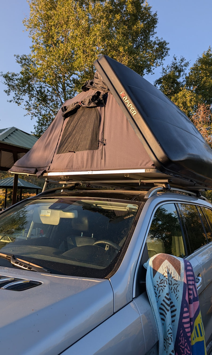 Silver SUV with an iKamper rooftop tent set up for camping, a compact RV rental alternative for outdoor adventures.