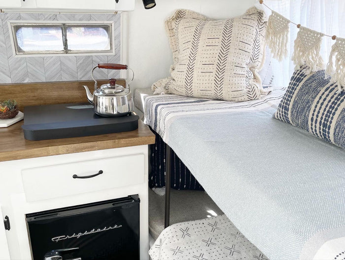 Cozy RV rental interior featuring a compact kitchen with kettle, Frigidaire fridge, and a stylish sleeping nook.