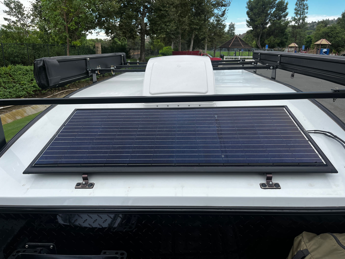 Overhead view of an RV rental roof featuring a large solar panel, roof rack, and side awnings for off-grid adventures.