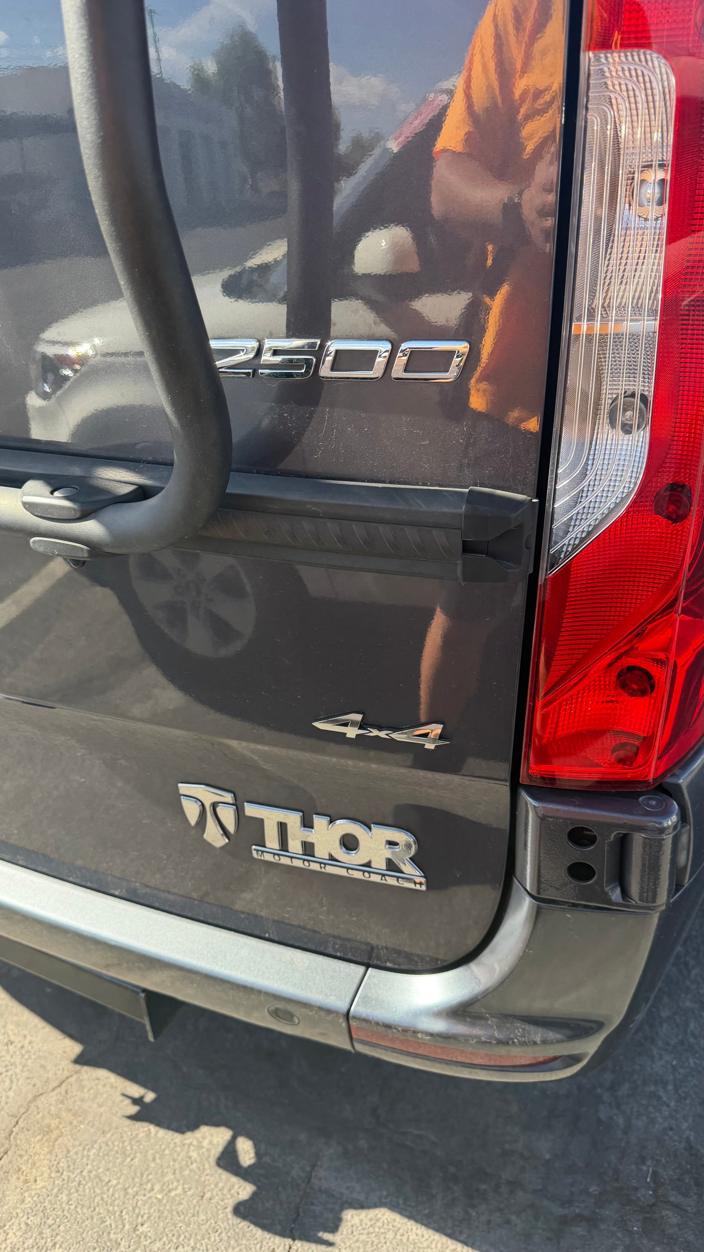 Thor 2500 4x4 RV rental rear view. Dark grey van with emblems, bike rack, and red taillight.