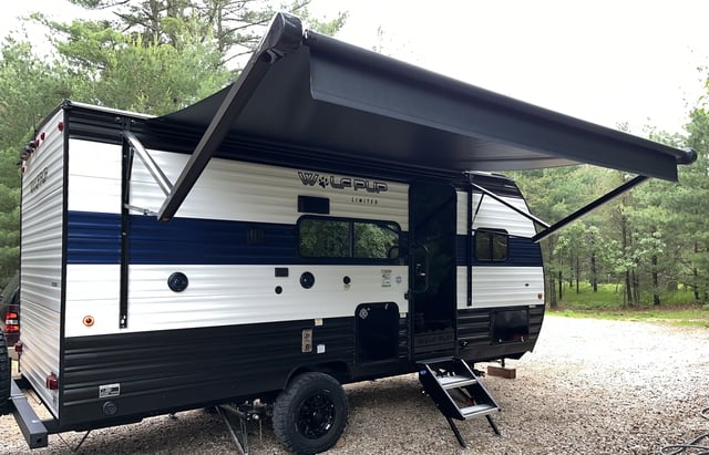 RV rental: a white & blue travel trailer with black awning extended