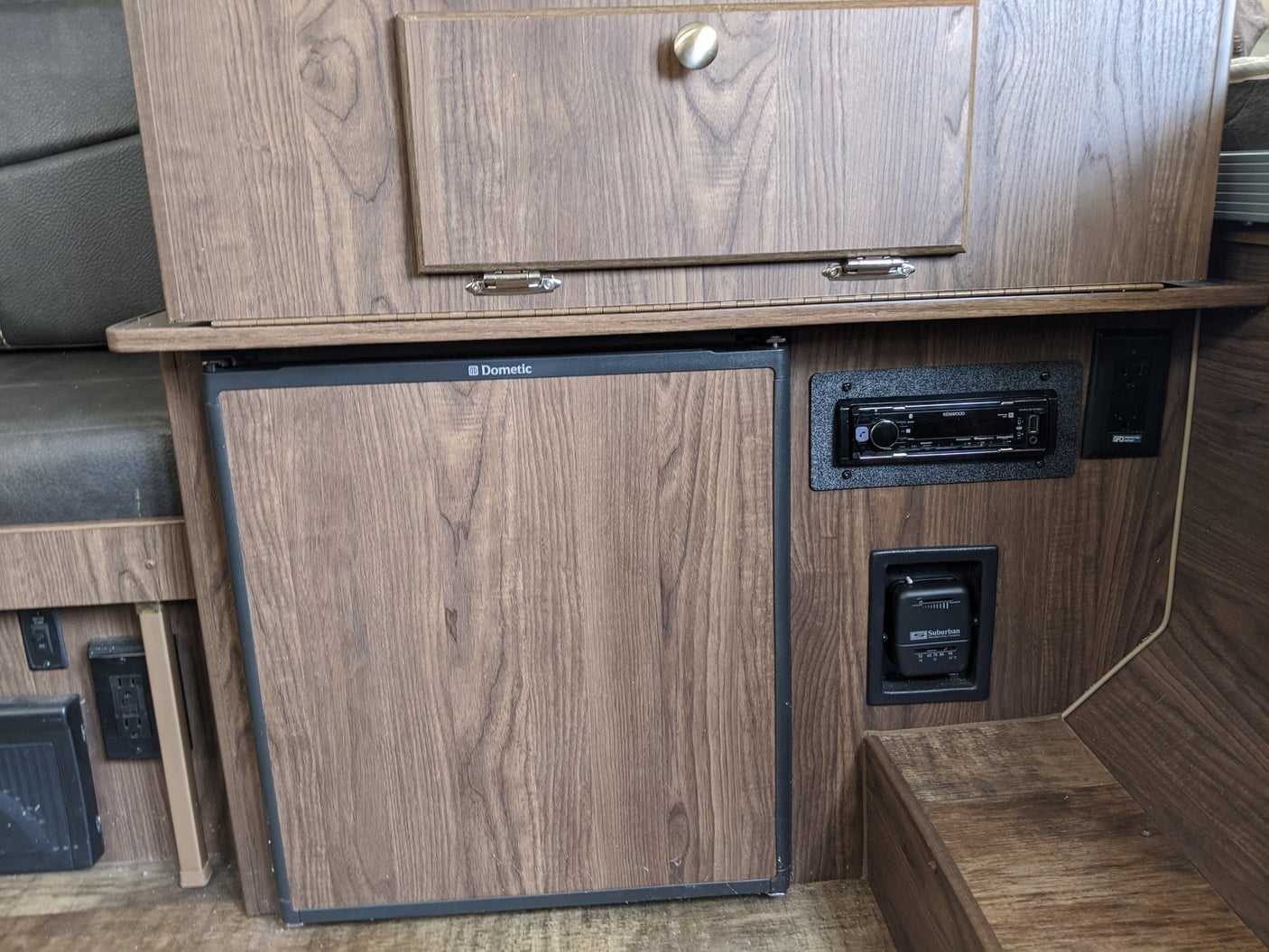 RV rental: Compact interior with wood-grain panels, Dometic fridge, Kenwood stereo, Suburban thermostat, and power outlets.