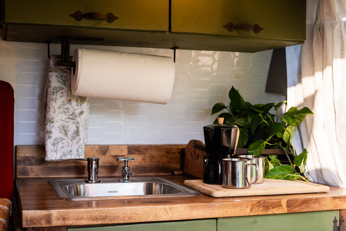 RV rental kitchen: wooden counter, sink, paper towels, moka pot, and mugs ready for your travels.