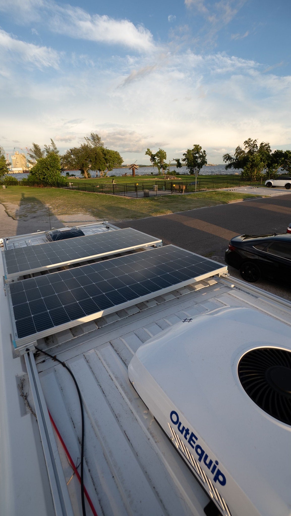 RV rental with rooftop solar panels and OutEquip AC unit, providing a scenic view of a waterfront park. — photo 6