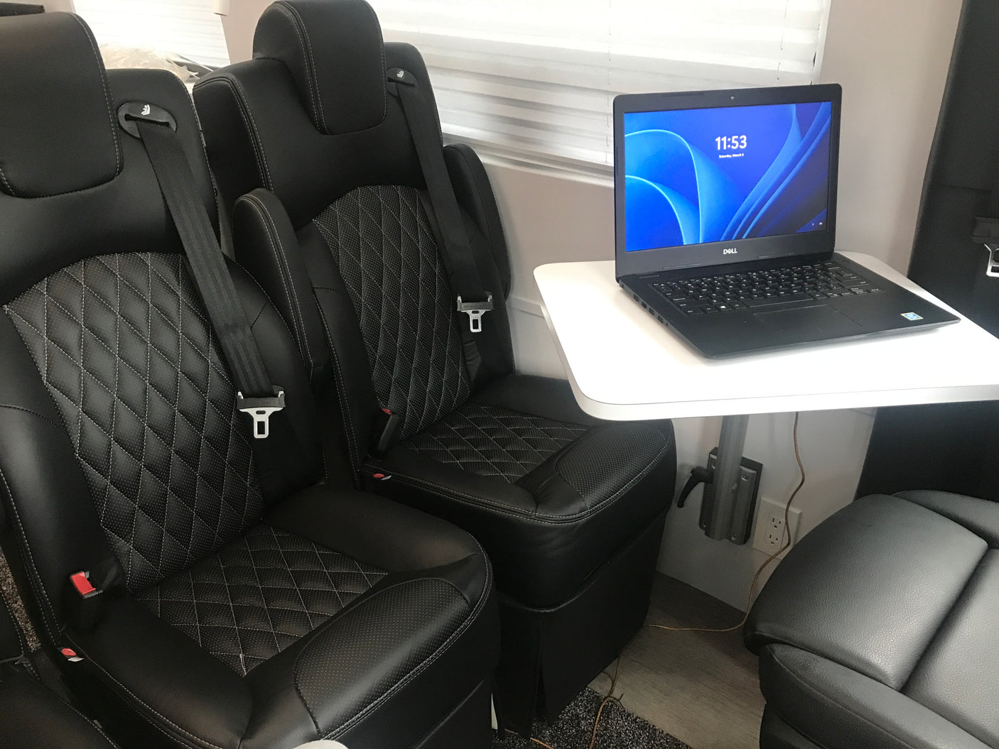 RV rental interior featuring plush seating, laptop on table, and convenient power. Perfect for travel & work.