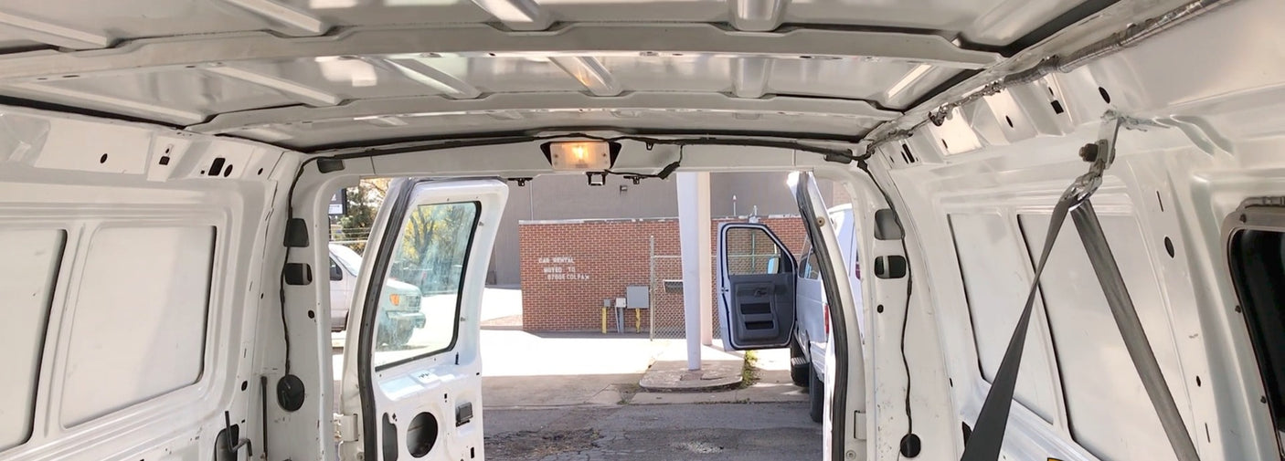 Inside a spacious white rental van, doors open, showing the unpaneled interior—perfect for an RV rental build.