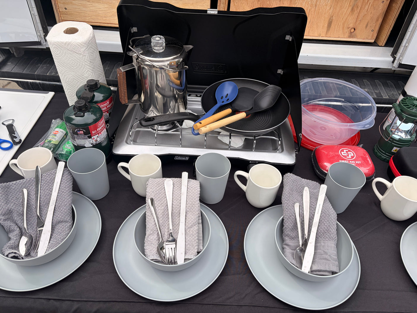 Perfect RV rental kitchen setup: Coleman stove, coffee percolator, propane, utensils, and dinnerware for convenient camping meals.