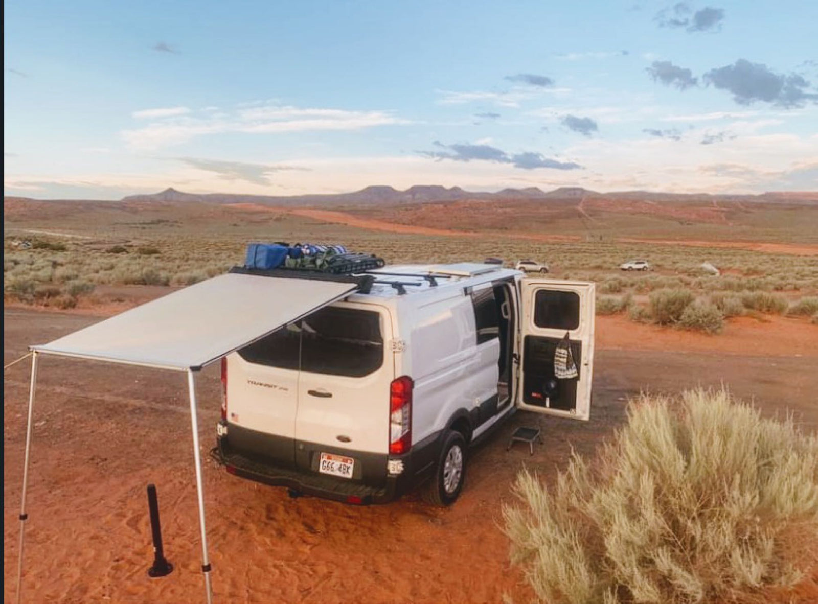an ideal RV rental. Features a roof rack and rugged tires for your next travel adventure.|A white Ford Transit camper van