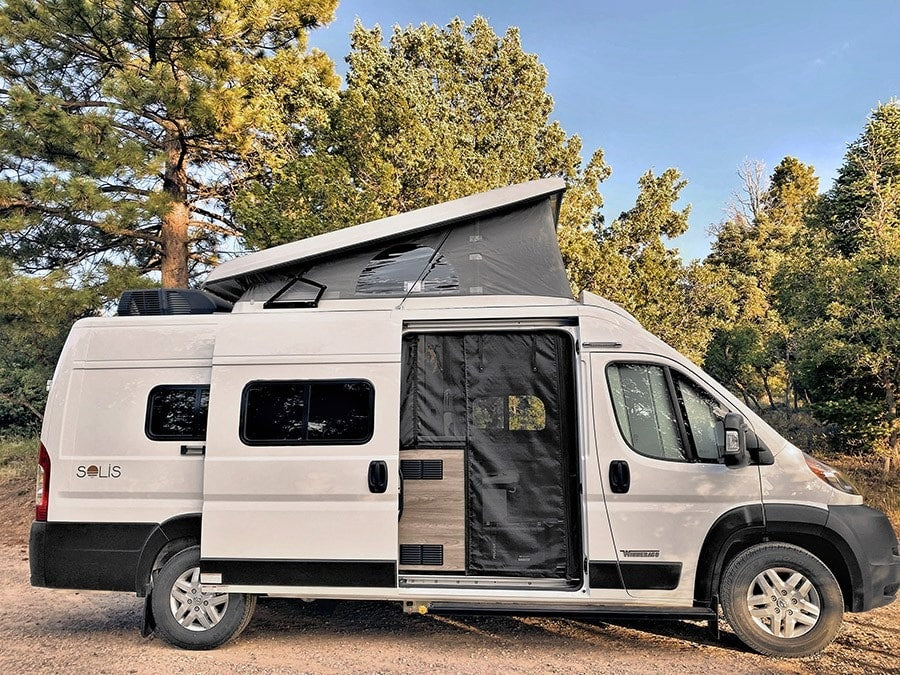 parked on gravel outdoors. Ideal for your next RV rental.|This white Winnebago Solis camper van