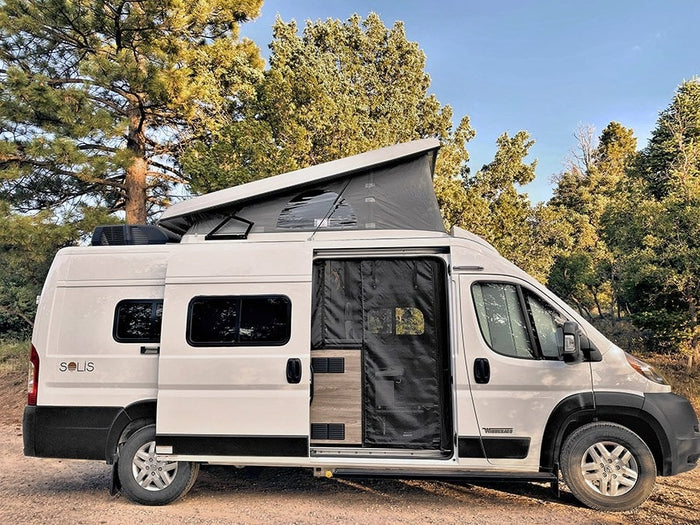 parked on gravel outdoors. Ideal for your next RV rental.|This white Winnebago Solis camper van
