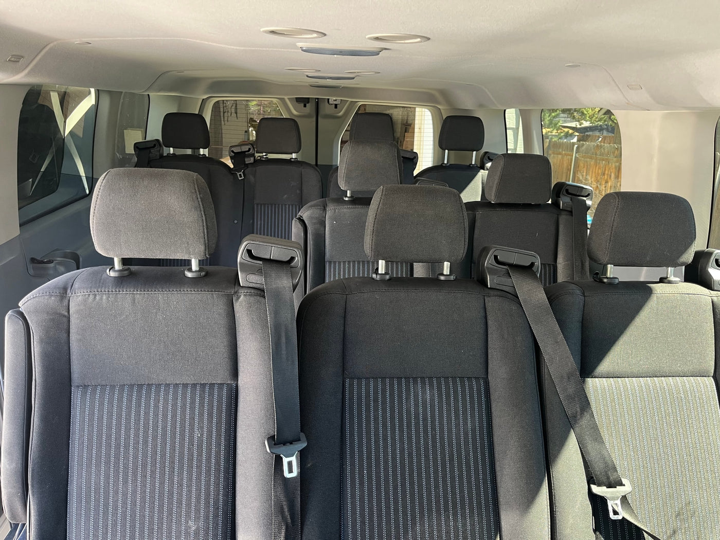 Interior of an RV rental van, showing multiple rows of black fabric passenger seats with headrests and seatbelts. — photo 3