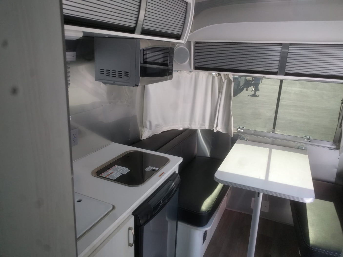 Cozy rv rental interior with kitchenette, dinette, microwave, & panoramic window. Perfect for your next adventure.
