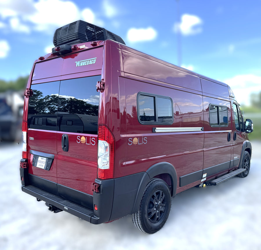 Maroon Winnebago Solis RV rental parked outdoors under a blue sky, featuring a roof-mounted AC unit.