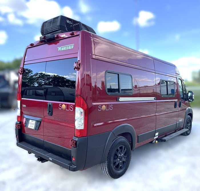 Maroon Winnebago Solis RV rental parked outdoors under a blue sky, featuring a roof-mounted AC unit.