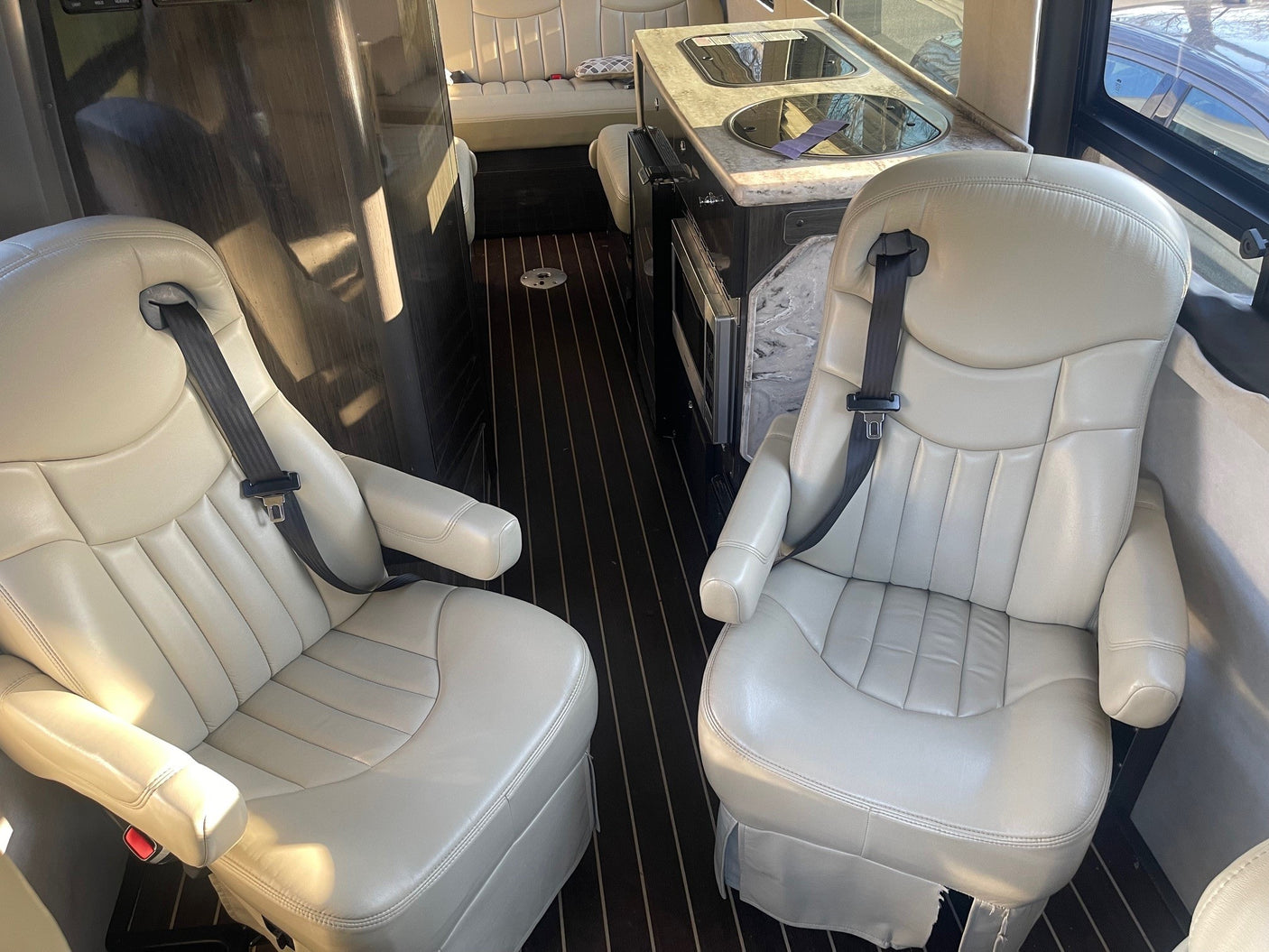 and rear convertible seating/bed.|RV rental interior: Comfortable beige leather captain's chairs