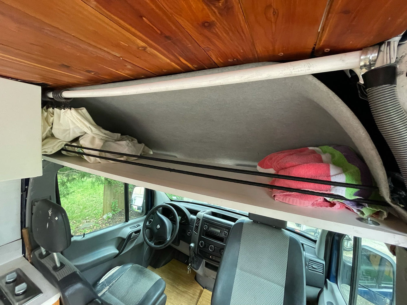 RV rental interior: Front cabin, dashboard, and overhead storage bunk with a warm cedar ceiling. — photo 13