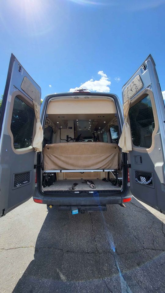 is parked at an auto repair shop under a blue sky.|Spacious RV rental cockpit with tan captain's seats
