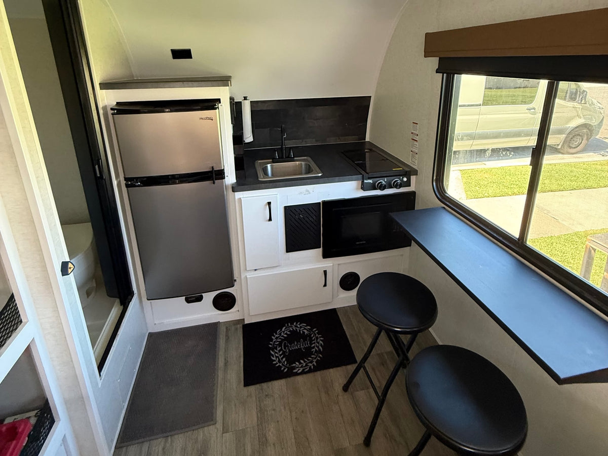 ready for adventure.|Side view of a "MODERN GATHERER" RV rental with its main door and screen door open — photo 4