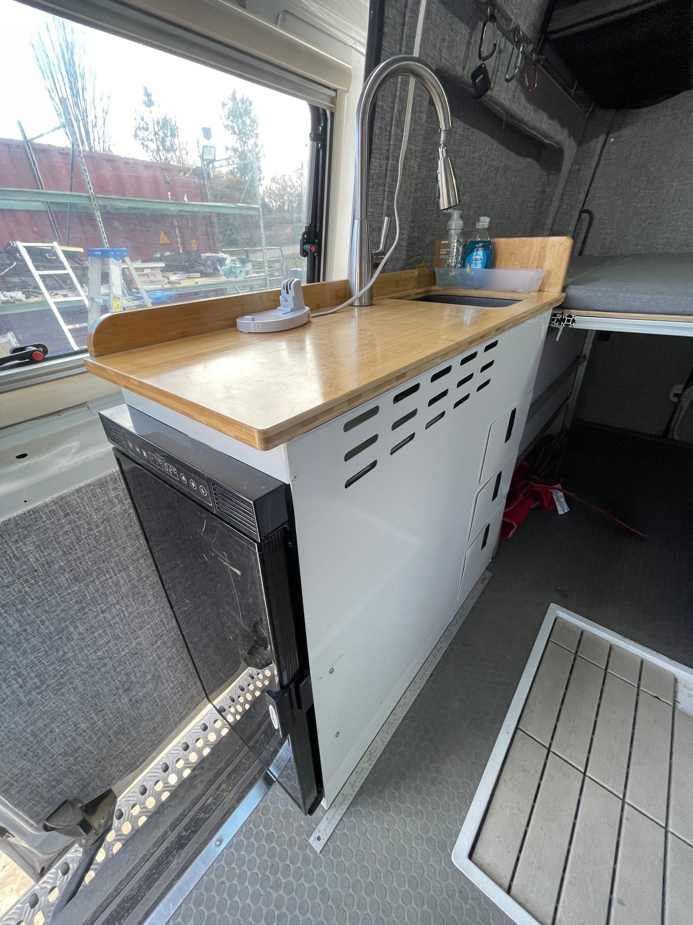 and modular grey bed cushions for comfortable travel.|Inside a functional RV rental: compact kitchenette — photo 8