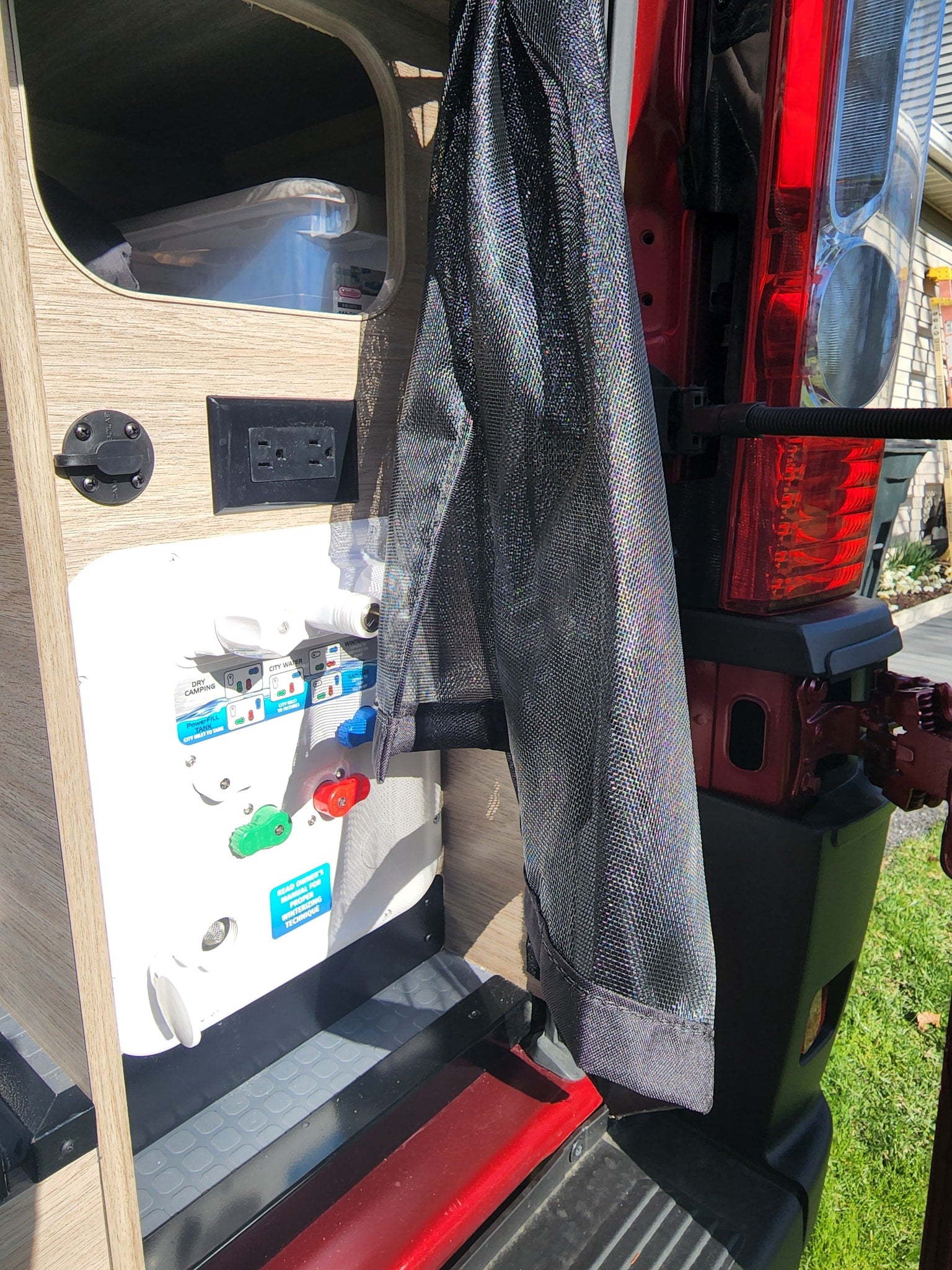 Inside an RV rental: rear utility area with water system controls, power outlet, and solar input for adventures.