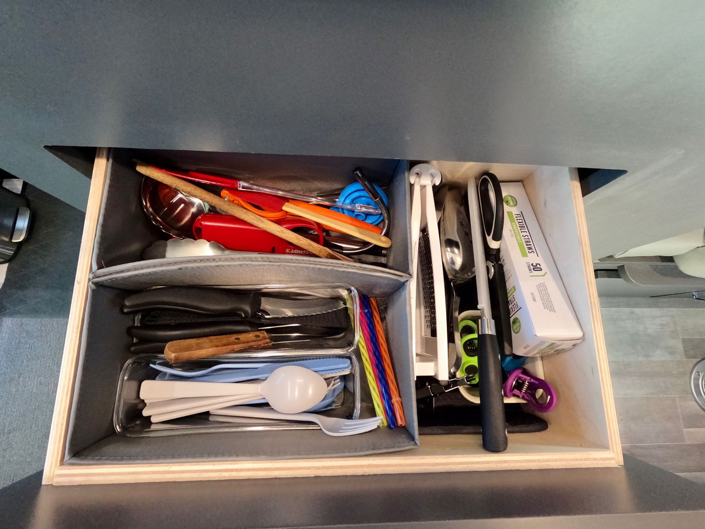 This RV rental kitchen drawer is neatly organized with a variety of utensils, including knives, spatulas, forks, and straws.