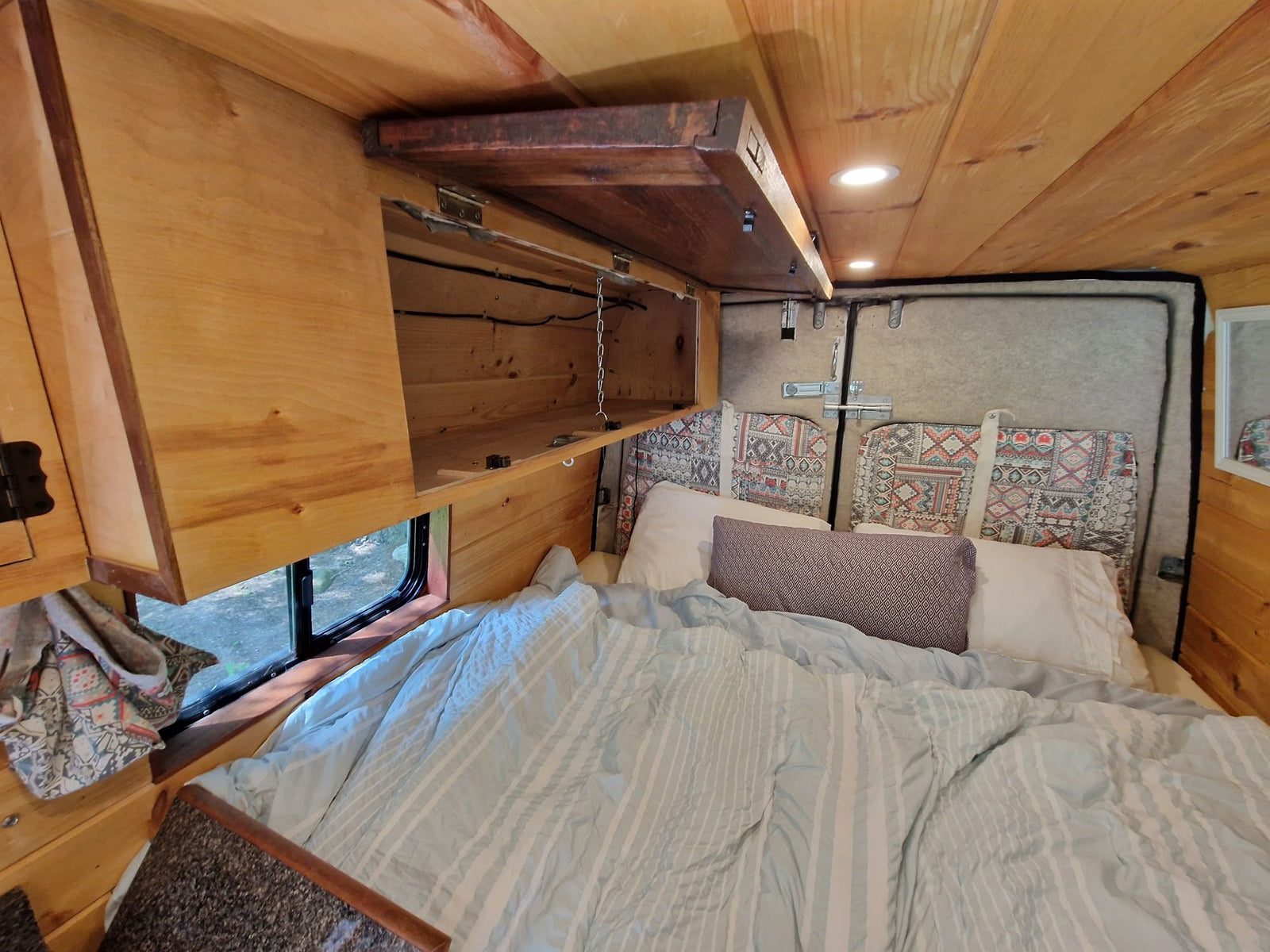 and cushioned bench seating.|Explore this charming RV rental: a wood-paneled camper van interior with a kitchen