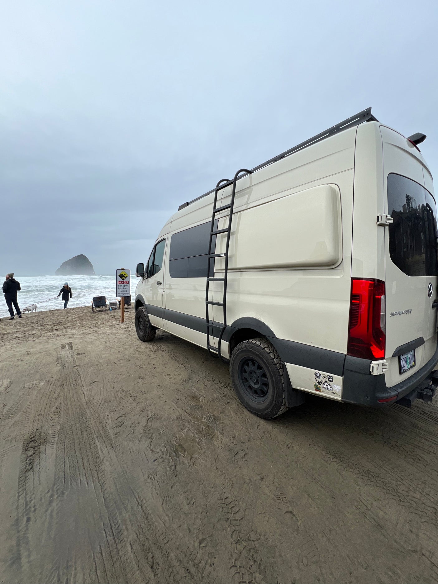 This RV rental Sprinter van, equipped for adventure, is parked on a sandy beach overlooking the ocean.